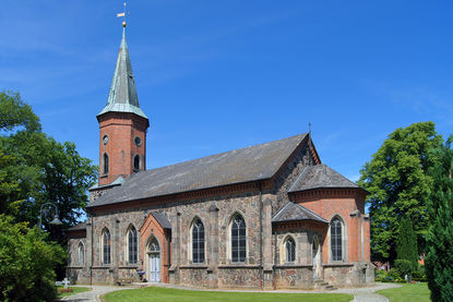 Kirche von rechts, vorn 2 Steige und Laterne links, grüne Eichen beidseitig, im Hintergrund rechts Gutsscheune - Copyright: Manfred Maronde
